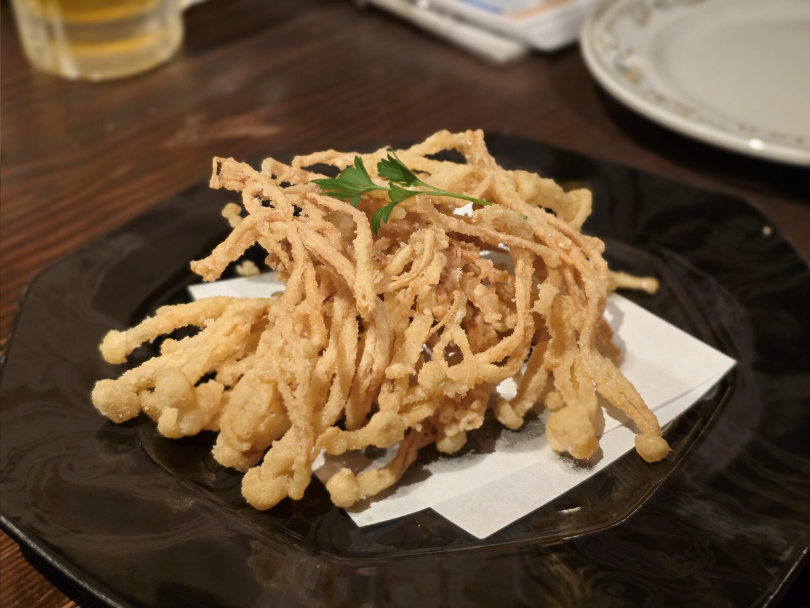 Crispy fried enoki mushrooms on black plate