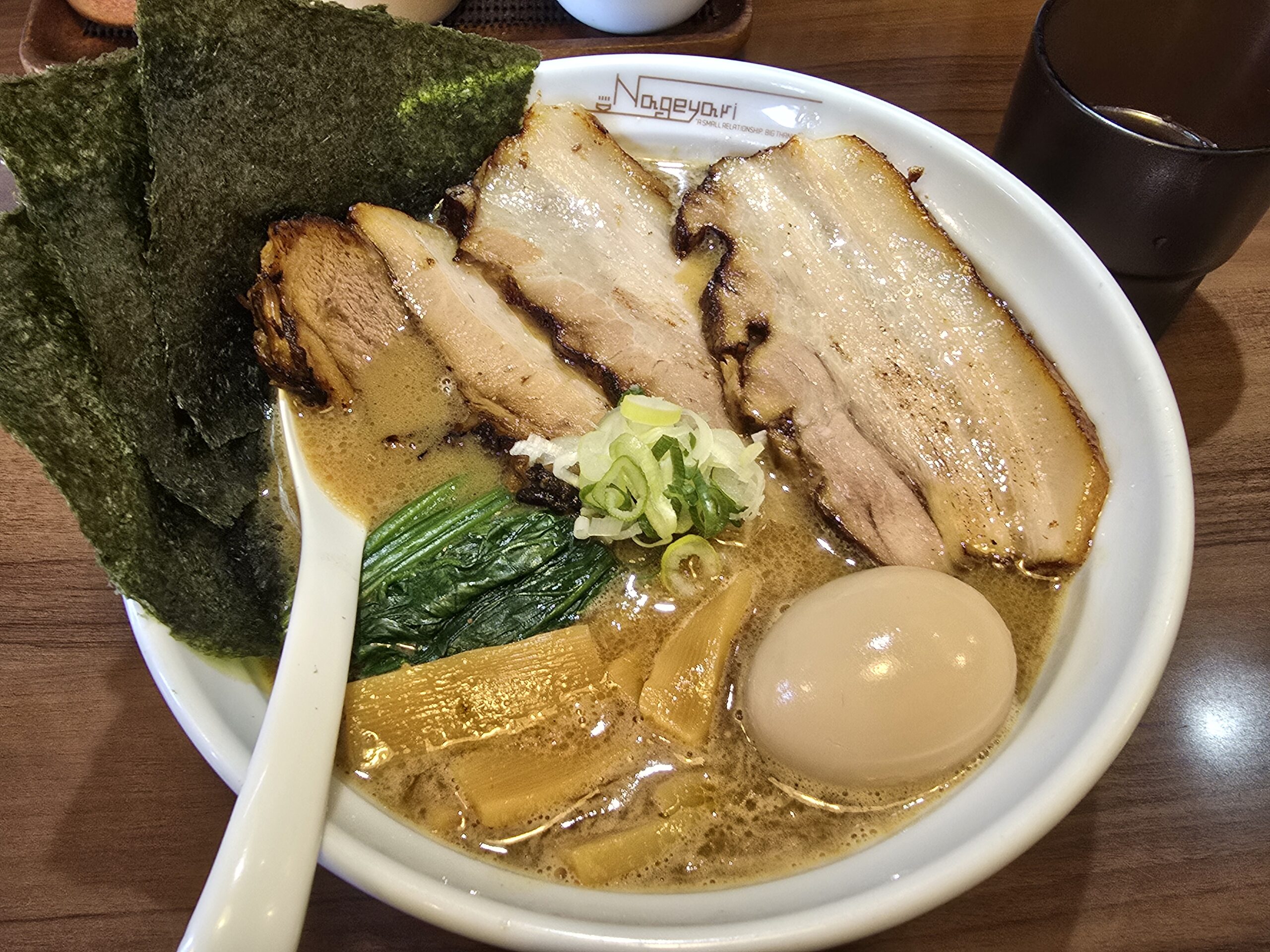 A steaming bowl of ramen from Nageyari in Gifu, topped with thick slices of char siu pork, seasoned egg, spinach, bamboo shoots, and seaweed in a rich pork-and-seafood broth.