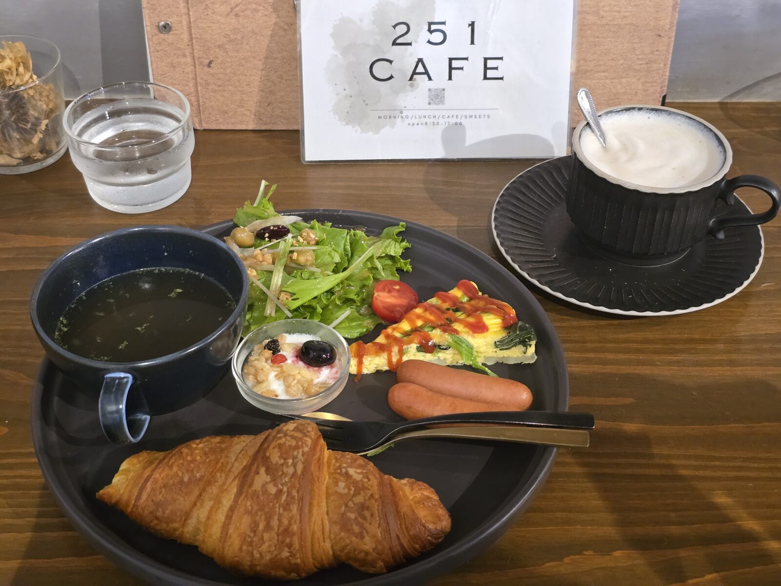 The Morning Set at 251 Café in Gifu — a croissant, sausages, salad, omelet, yogurt with granola, soup, and a café latte served on a sleek black plate.