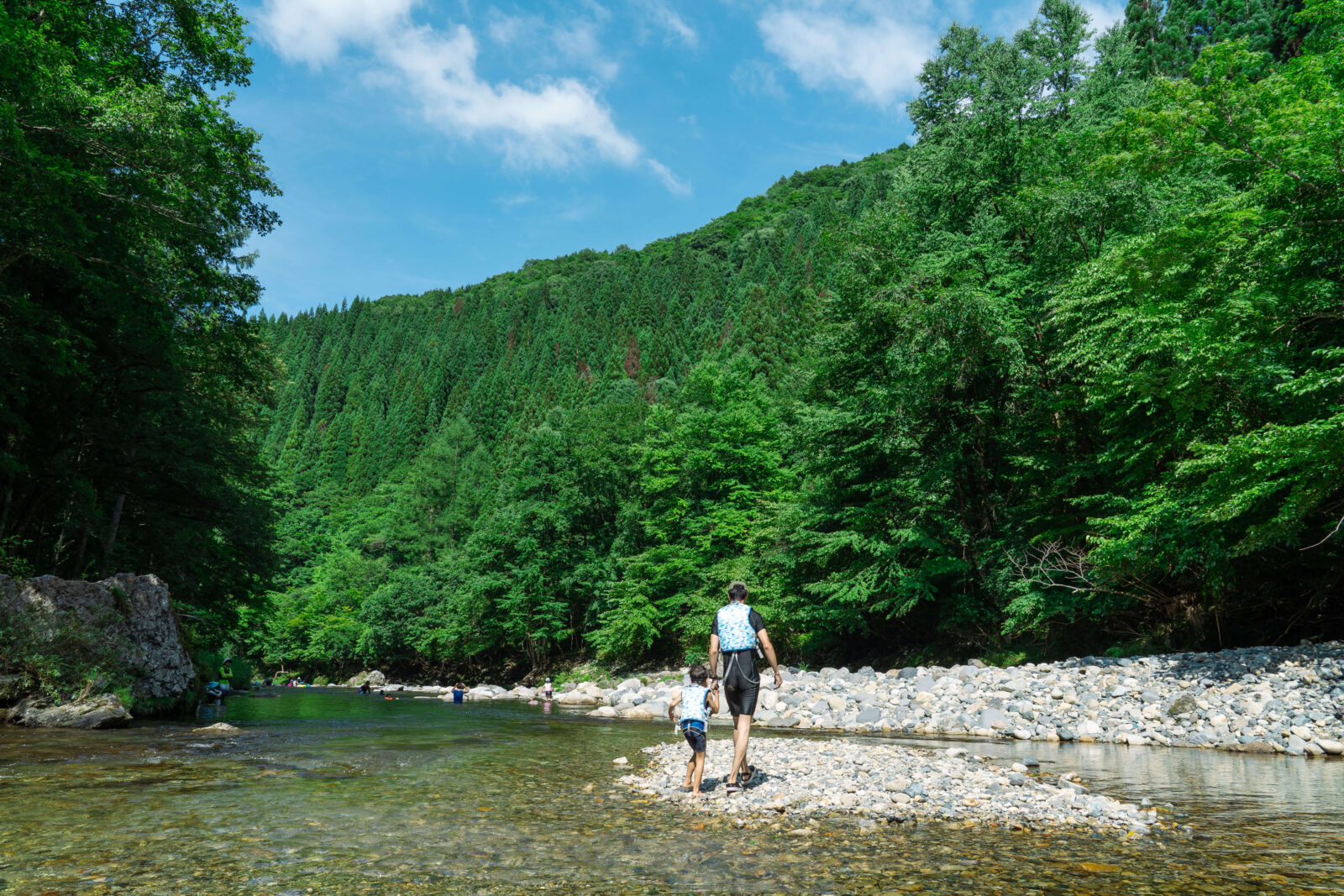 Father and child walking along the rocky riverside at Pascal Kiyomi Auto Campsite, Gifu.