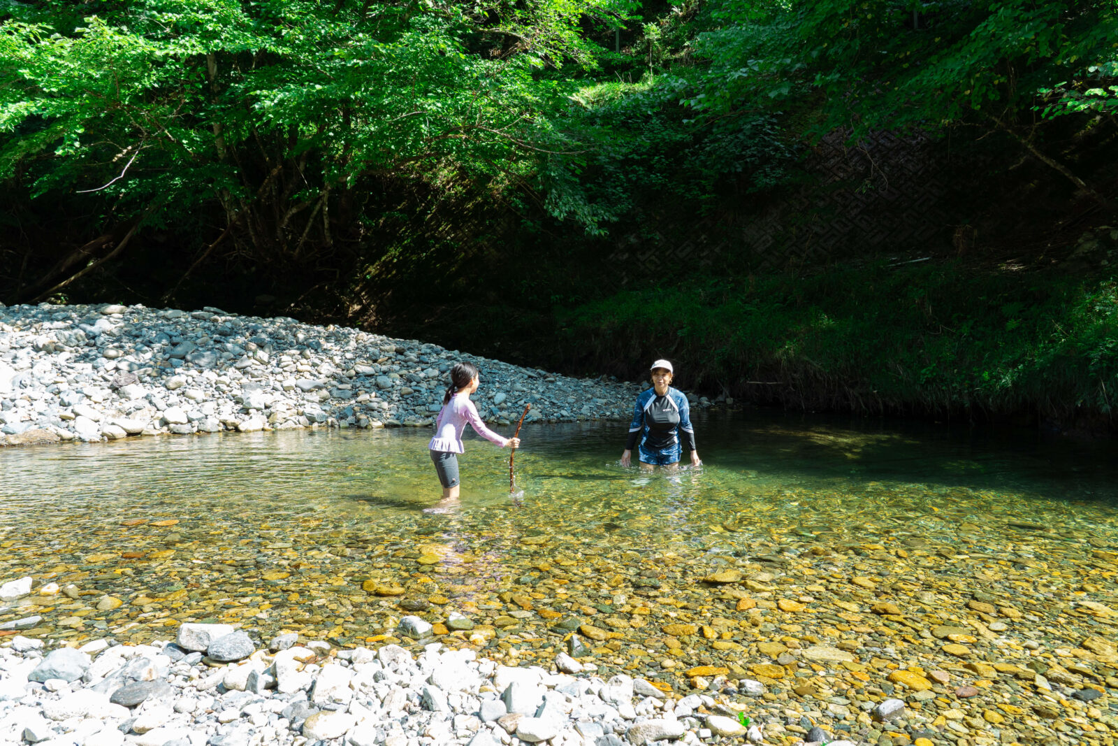Mother and daughter playing in shallow river water at Pascal Kiyomi Auto Campsite in summer.