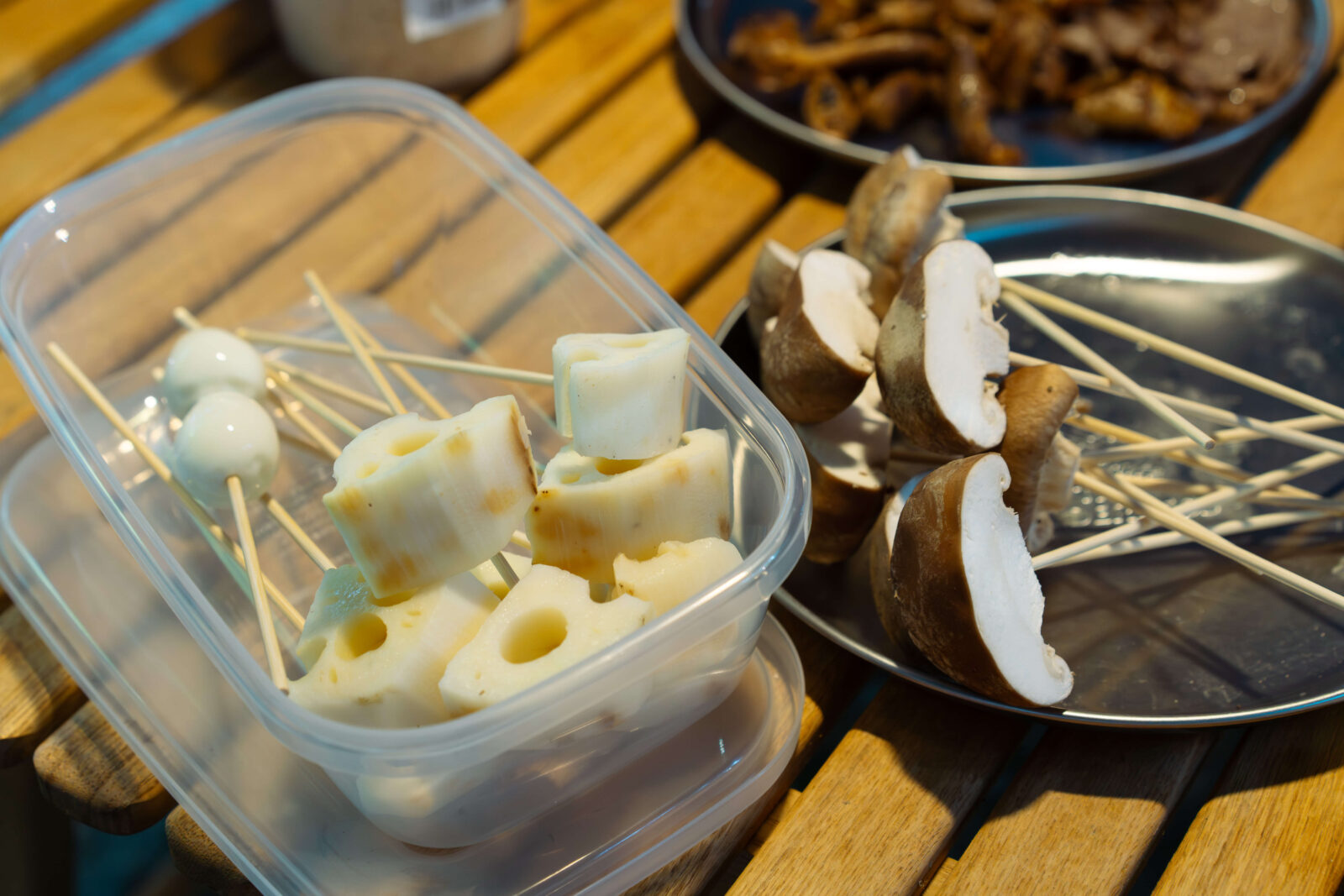 Fresh shiitake mushrooms and renkon skewers ready to grill at campsite barbecue.