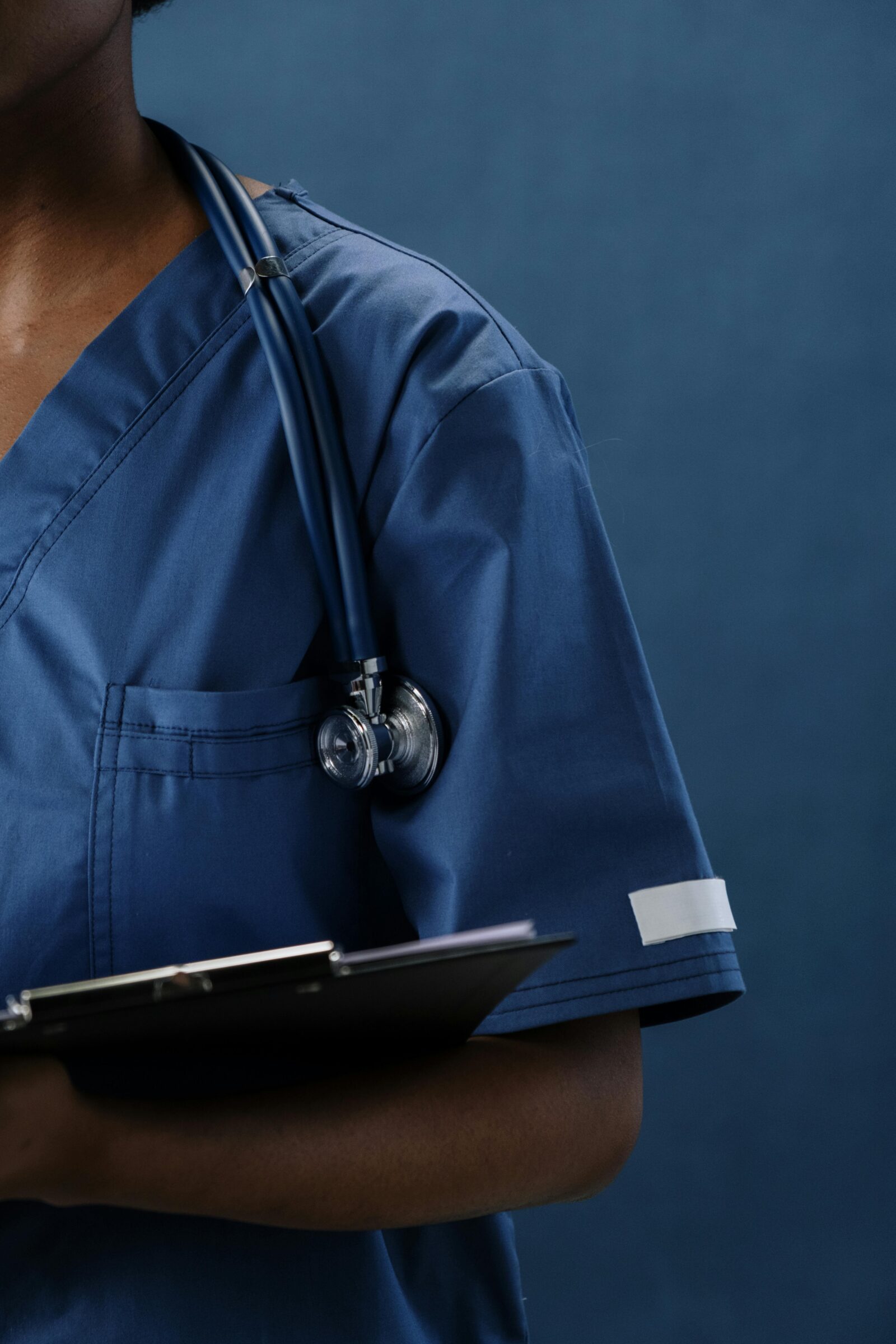 Healthcare professional in blue uniform holding a clipboard, representing focus and dedication in medical work.