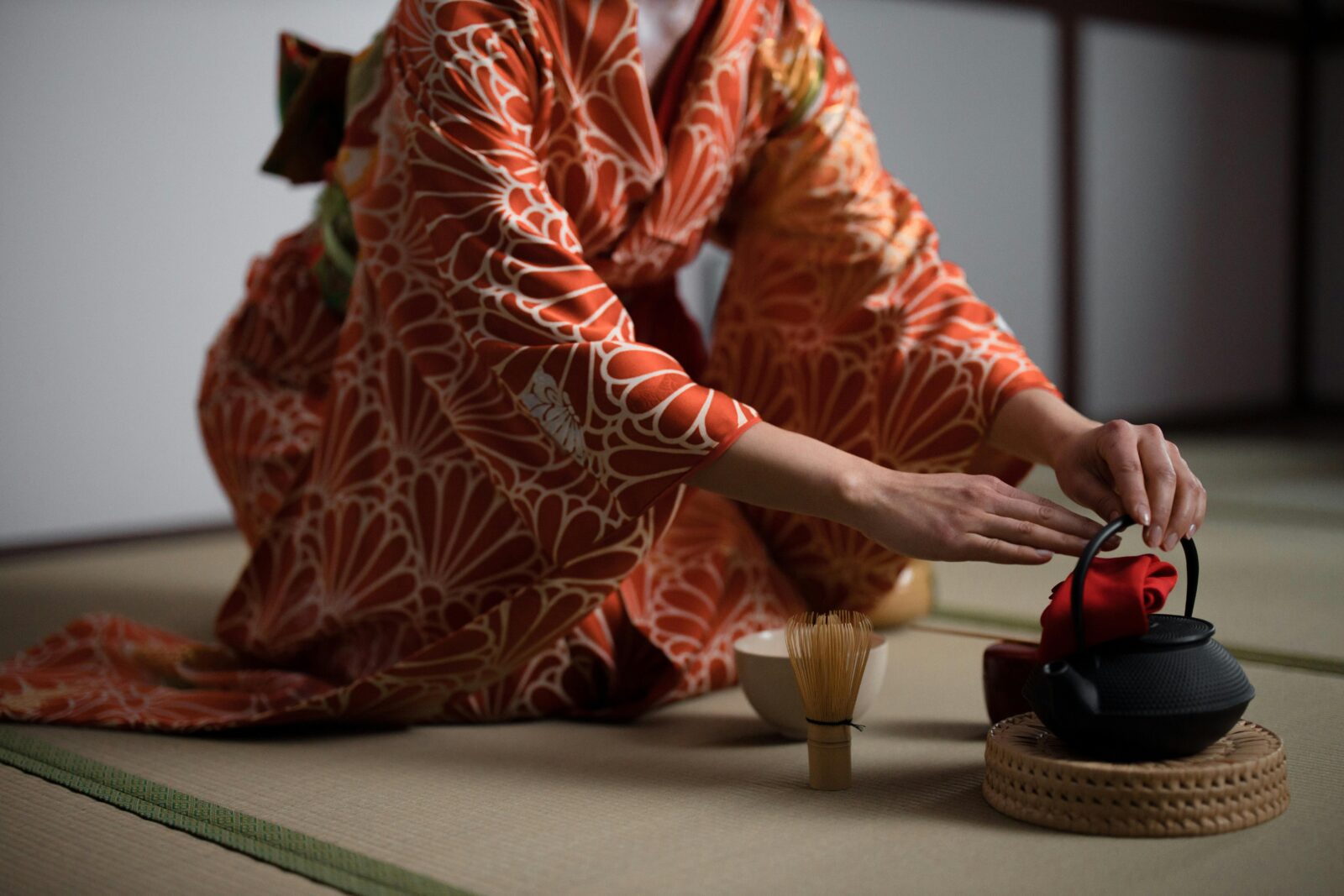 Japanese tea ceremony scene with woman in kimono, performing omotenashi through graceful tea preparation.