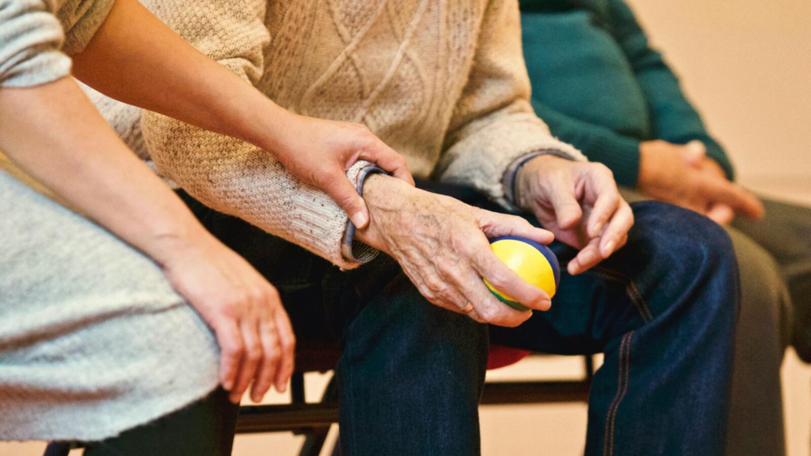 Close-up of caregiver assisting an elderly person during a rehabilitation activity, symbolizing teamwork and trust.