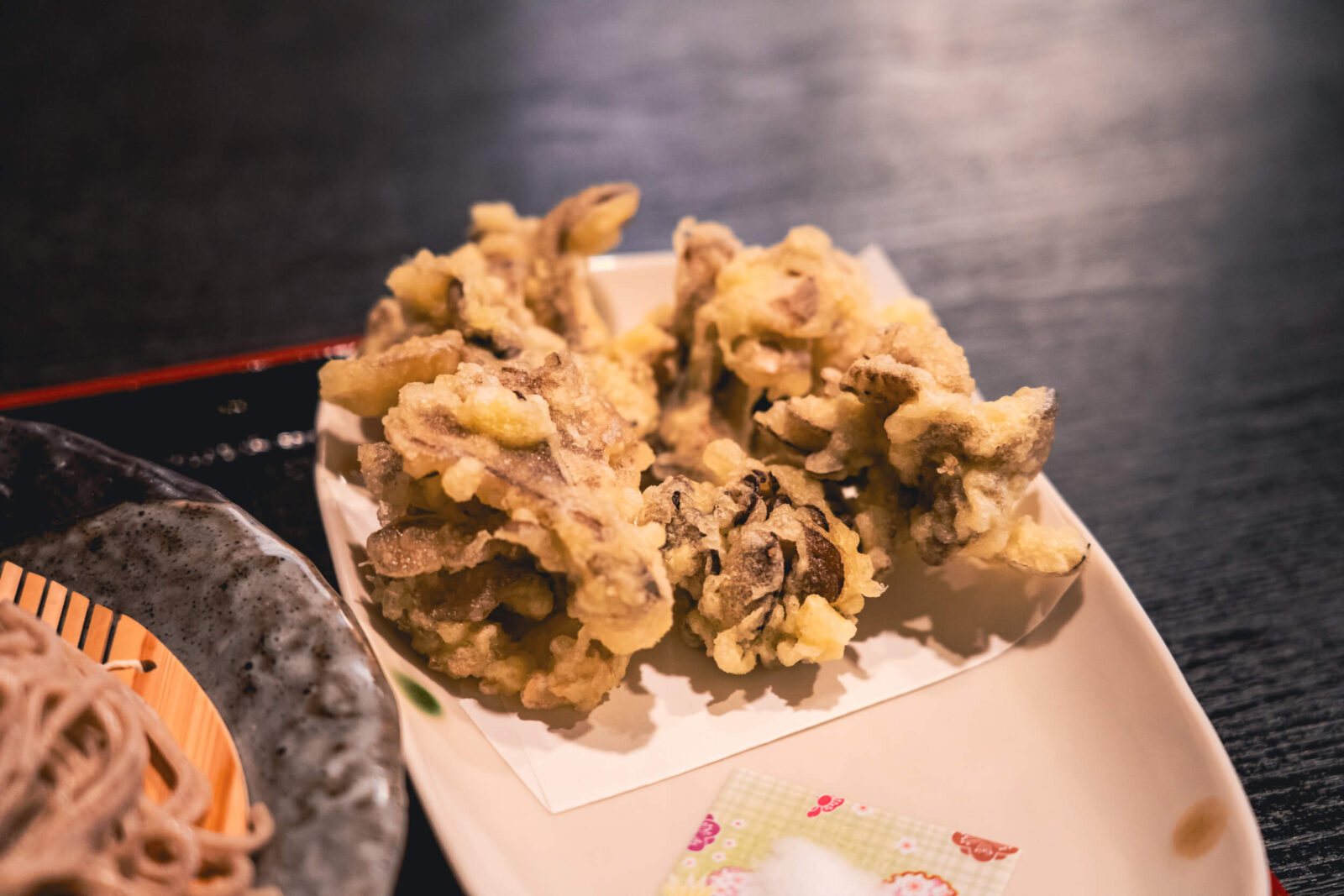 A close-up of crispy maitake mushroom tempura served on a plate in a Japanese restaurant.